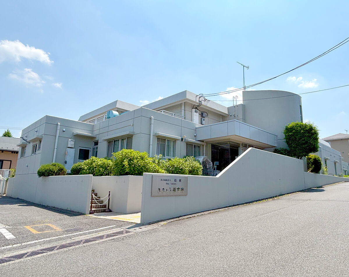 晴れた青空の下に建つ、グレーの外壁と曲線的なデザインが特徴的な「ききょう保育園」の外観。