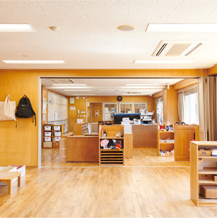 部屋の中央が広く開けられた保育室。パーテーションのように置かれた棚の奥には、作業スペースがある。
