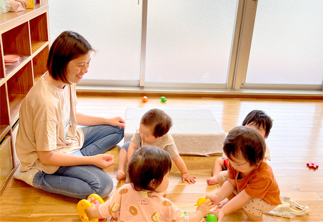 室内で保育士とボール遊びを楽しむ子どもたち