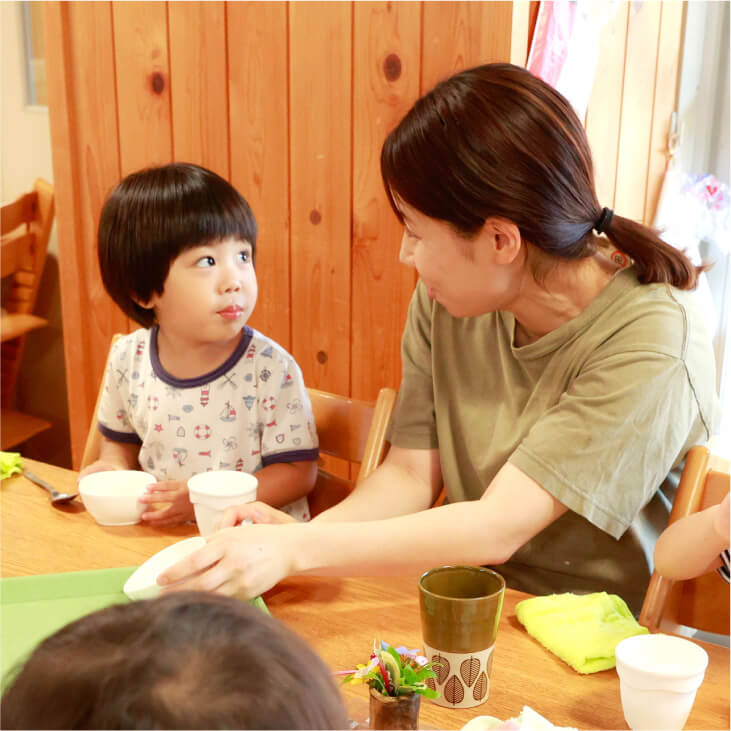 食事中に保育士と顔を見合わせる子ども