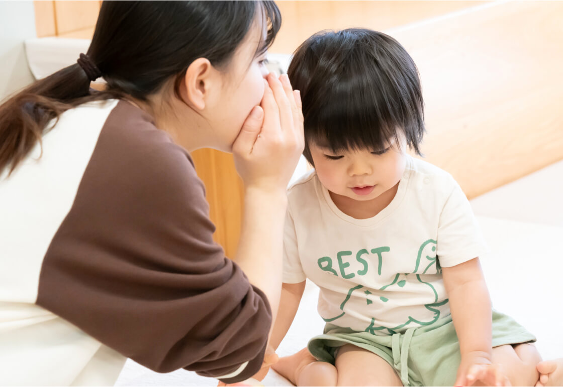 子どもにこそこそ話をする保育士