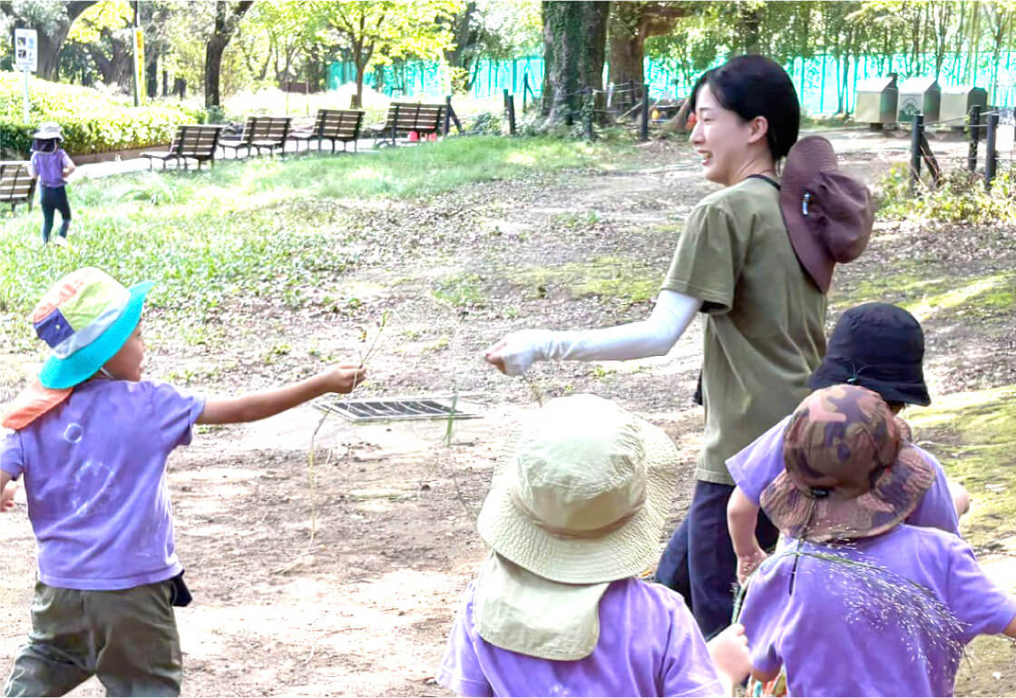 自然豊かな公園で子どもたちと一緒に走る保育士