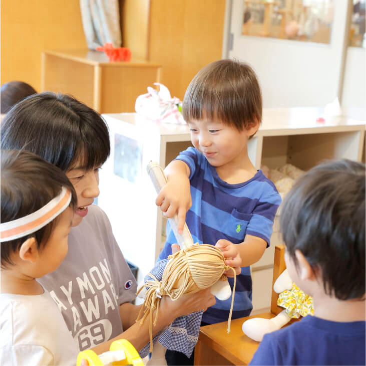 毛糸を手にした保育士と子どもたち