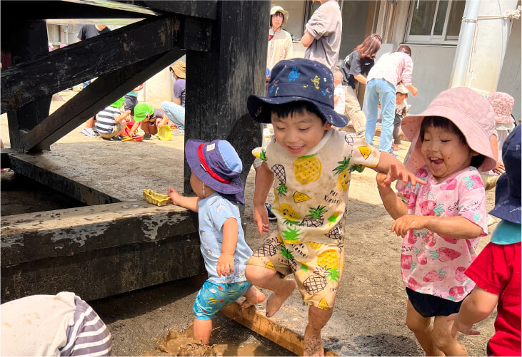 泥んこになりながら、水や砂の感触を全身で楽しむ笑顔の子どもたち