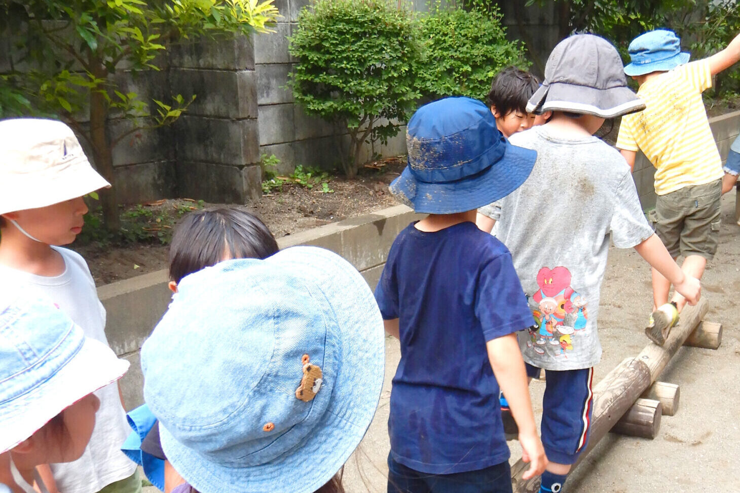 東北沢ききょう保育園の園庭に置いてある木の上を渡る子ども等