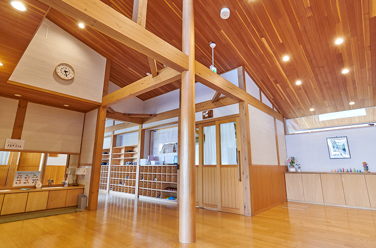 高い天井と太い木の柱・梁が特徴的な施設内のホール。左手には手洗い場があり、奥には木製のロッカーや下駄箱が並んでいる