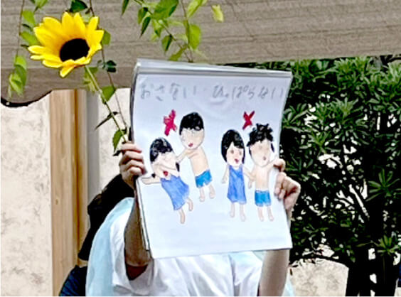 プールで子どもたちに注意事項を説明する保育士