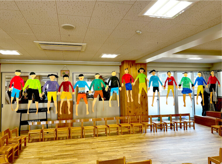 卒園の会の会場に、子どもたちが描いた絵が一列に展示されている様子