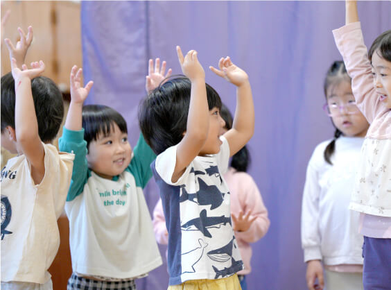 パーティーで両手を上げて笑い合う子どもたち