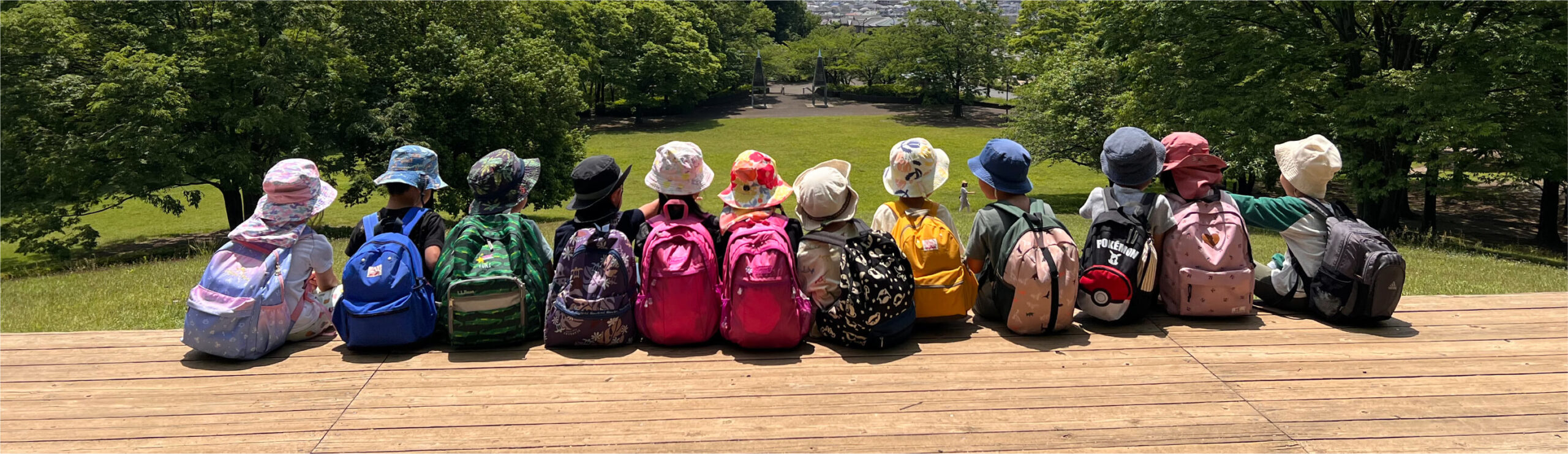 原っぱに座って、自然豊かな風景や街並みを眺める子どもたち