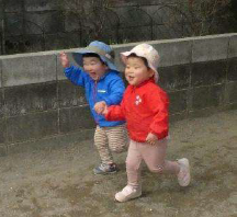 手をつないで笑顔で走る2歳児