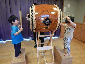 おめでとう集会で太鼓をたたく2歳児